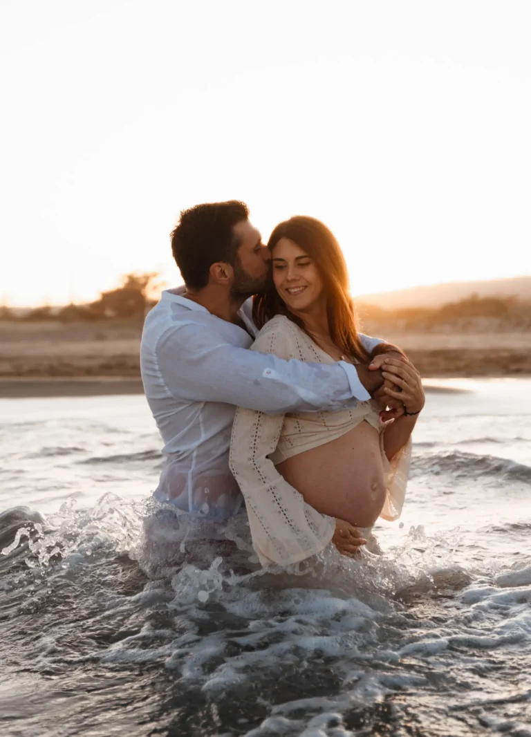 Photos d'une séance grossesse d'un couple s'enlaçant dans la mer à Gruissan